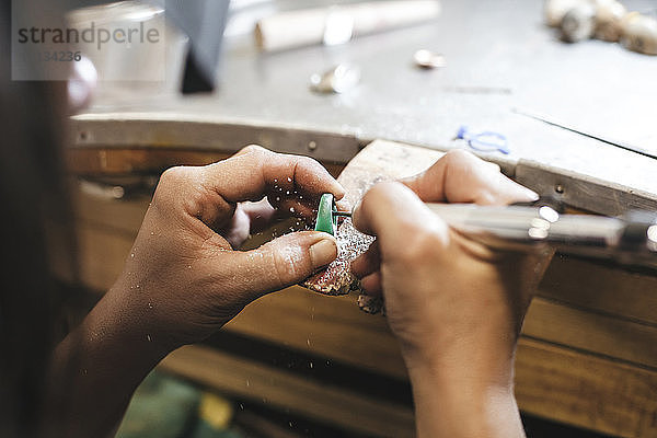 Geschliffene Hände weibliche Kunsthandwerkerin formt Ring mit Ausrüstung auf Tisch in Werkstatt