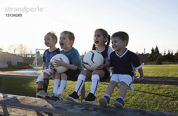 Kinder schreien  während sie bei Sonnenuntergang gegen den klaren Himmel auf den Park schauen