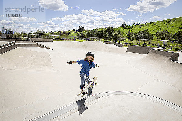 Hochwinkelansicht eines Jungen  der auf einer Rampe Skateboard fährt