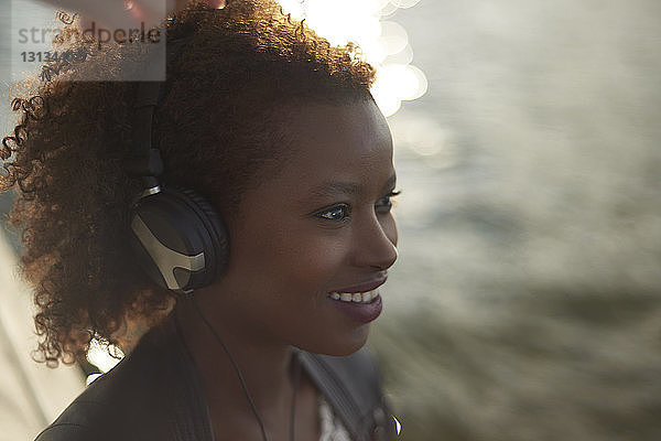 Hochwinkelansicht einer glücklichen Frau  die Musik hört  während sie am See steht