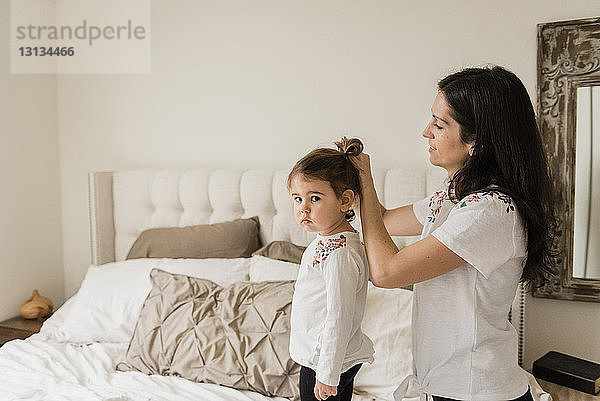 Porträt einer traurigen Tochter mit einer Mutter  die sich zu Hause die Haare bindet