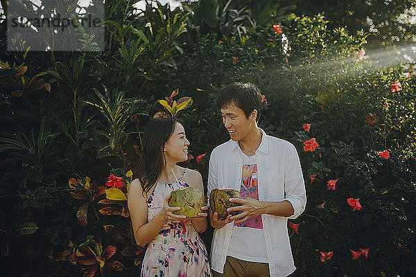 Ehepaar unterhält sich beim Trinken von Kokosnusswasser im Park