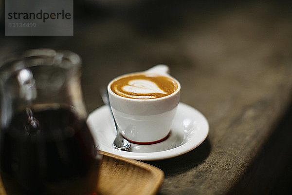 Hochwinkelansicht eines Cappuccinos  der auf einem Café-Tisch serviert wird