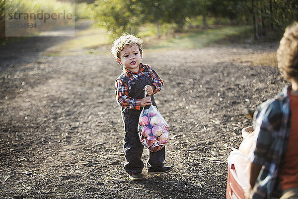 Junge  der eine Plastiktüte mit Früchten trägt  während er auf der Strasse steht
