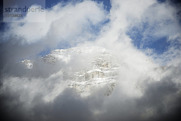 Tiefwinkelansicht der Wolken  die den schneebedeckten Berg im Ordesa-Nationalpark bedecken