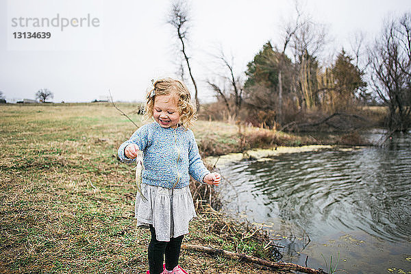 Fröhliches Mädchen hält Fische beim Angeln am See