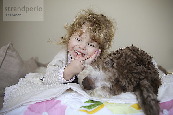 Glückliches Mädchen entspannt sich mit Hund zu Hause im Bett