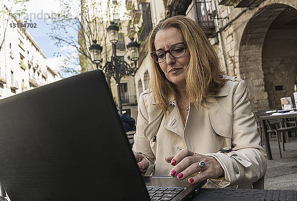 Niedriger Blickwinkel einer Geschäftsfrau mit Laptop-Computer auf einem Tisch in der Stadt