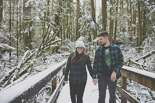Paar hält im Winter beim Waldspaziergang im Lynn Canyon Park Händchen