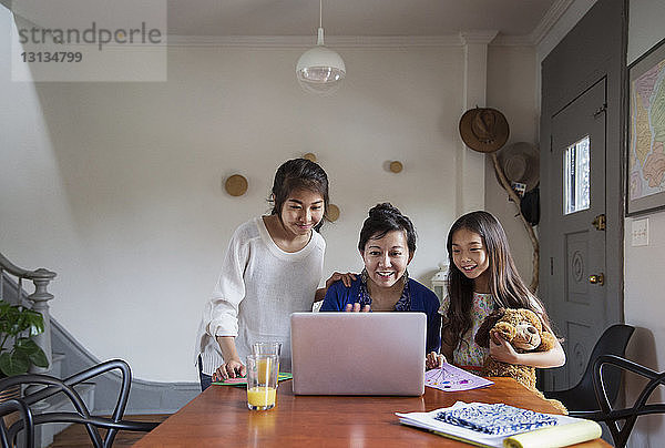 Glückliche Familie schaut zu Hause auf den Laptop auf dem Tisch
