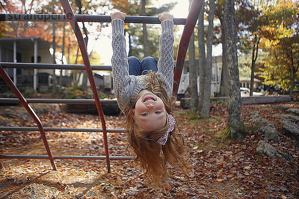 Porträt eines fröhlichen Mädchens  das im Herbst auf einem Spielplatz in einer Dschungelturnhalle spielt