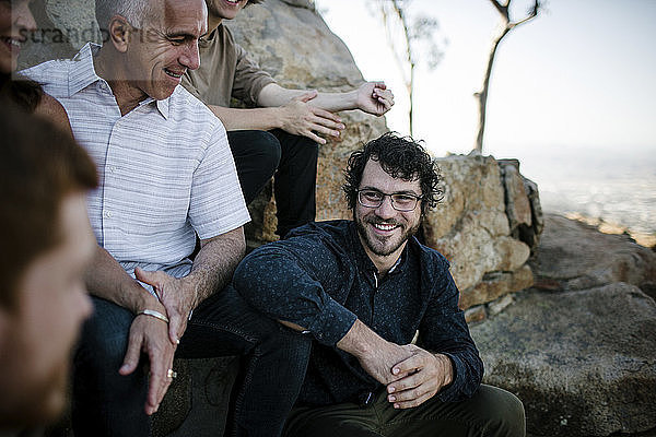 Glückliche Söhne im Gespräch mit den Eltern  während sie im Park bei Felsformationen sitzen