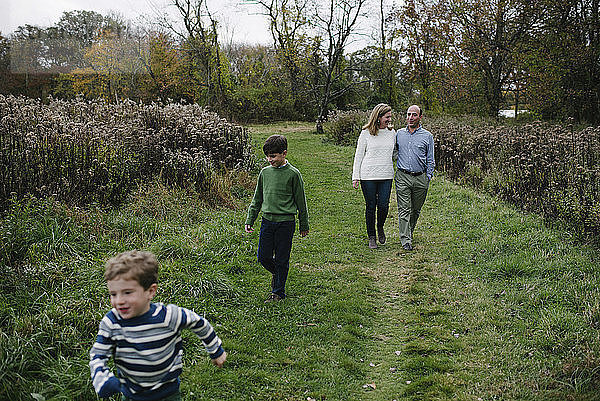 Hochwinkelaufnahme einer Familie  die auf einem Grasfeld im Park spazieren geht