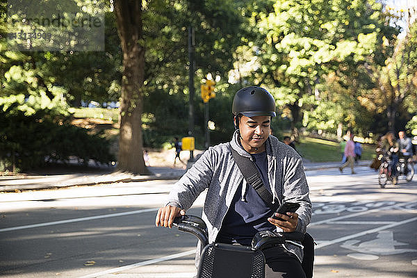 Mann benutzt Mobiltelefon beim Fahrradfahren auf der Straße in der Stadt