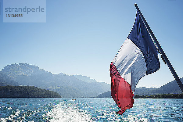 Französische Flagge über dem Annecy-See gegen klaren Himmel