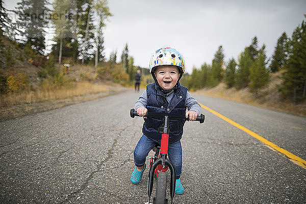 Porträt eines süßen  fröhlichen Jungen beim Fahrradfahren auf der Landstraße
