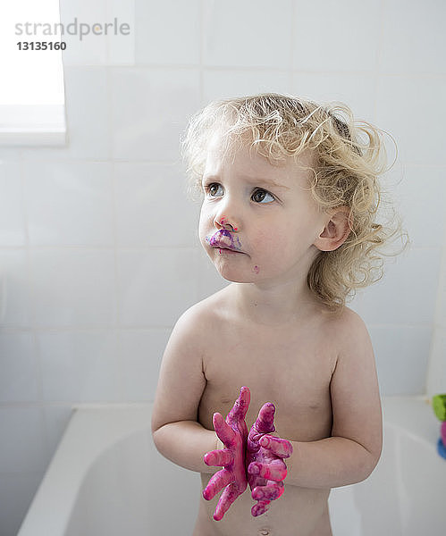 Mädchen schaut auf  während sie in der Badewanne steht