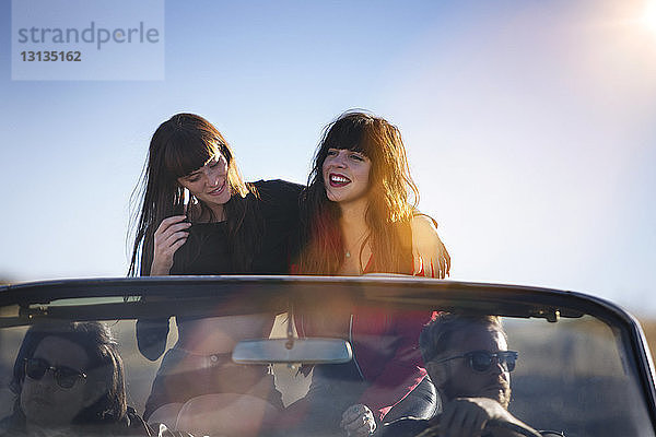 Freunde reisen im Cabrio gegen den klaren Himmel