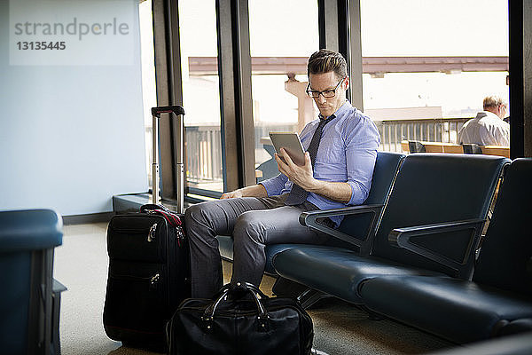 Geschäftsmann benutzt Tablet-Computer  während er im Wartebereich der U-Bahn-Station sitzt