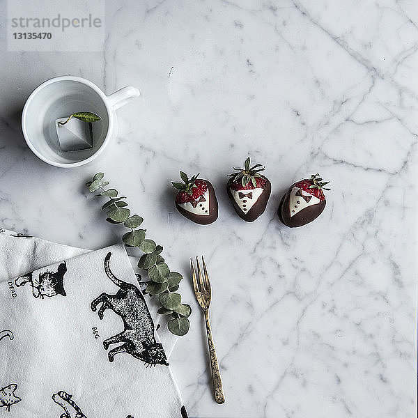 Draufsicht auf schokoladenüberzogene Erdbeeren mit Gabel auf dem Tisch