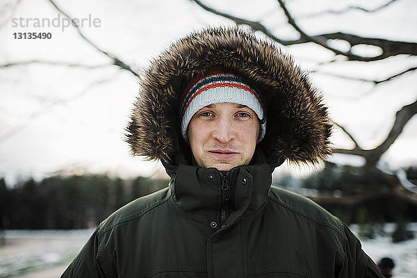 Porträt eines Mannes in warmer Kleidung  der im Winter gegen den Himmel steht