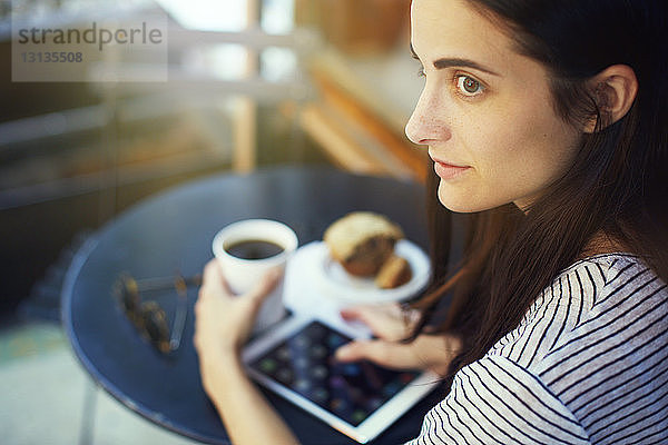 Nachdenkliche Frau sitzt am Tisch im Straßencafé