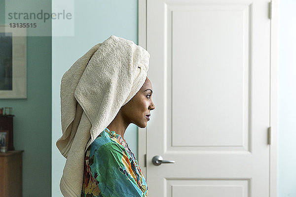 Seitenansicht Frau schaut weg  während sie ein Handtuch auf dem Kopf trägt