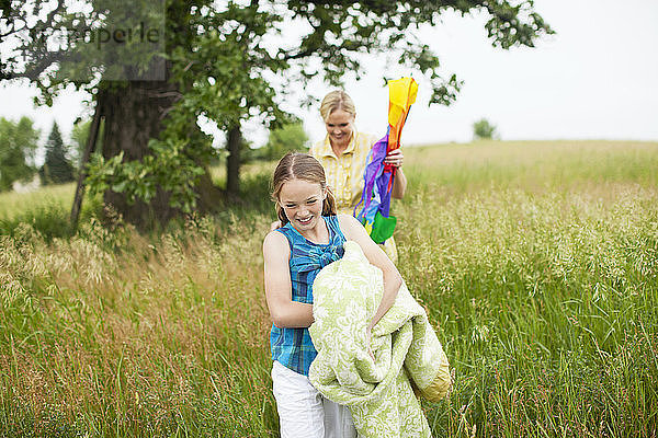 Glückliche Tochter und Mutter gehen auf Grasfeld