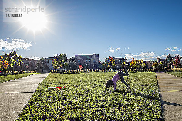 Verspieltes Mädchen  das an einem sonnigen Tag im Park auf Rasen spielt