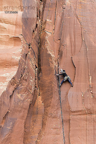 Rückansicht einer Wanderin beim Felsklettern