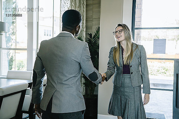 Geschäftsleute schütteln sich die Hand  während sie im Büro an der Tür stehen