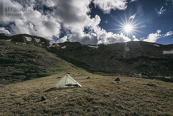 Zelt auf Berg gegen bewölkten Himmel bei Sonnenschein