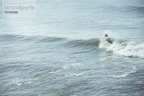 Mann surft auf einer Welle im Meer