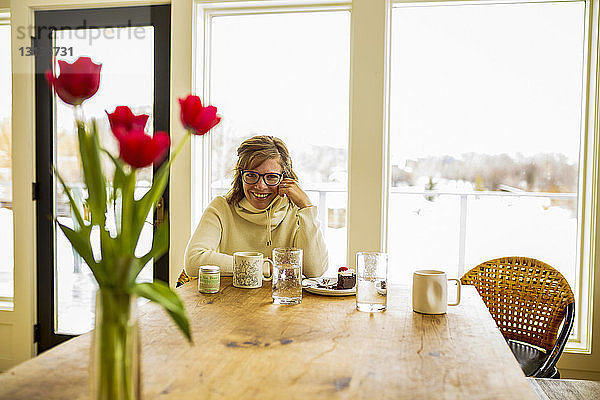 Porträt einer Frau  die zu Hause am Tisch sitzt
