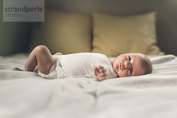 Porträt eines neugeborenen Jungen  der zu Hause auf dem Bett liegt