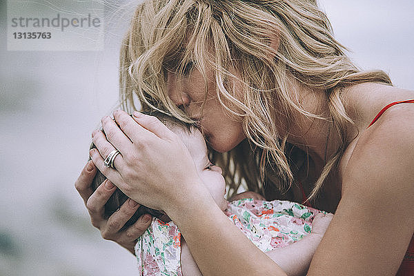 Frau mit blonden Haaren küsst Tochter