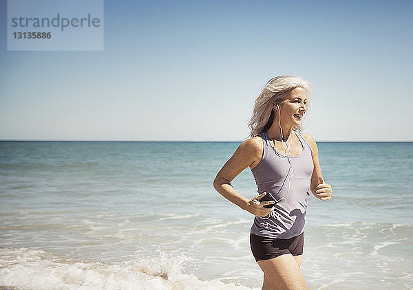 Volle Länge einer fitten Frau  die am Delray-Strand an der Meeresküste läuft