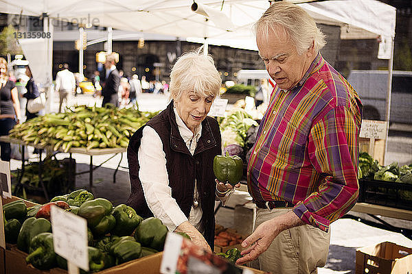 Älteres Ehepaar kauft grüne Paprika auf Straßenmarkt