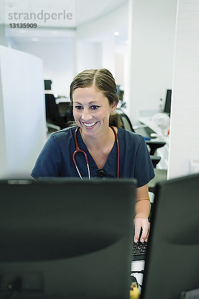 Fröhliche Ärztin benutzt Desktop-Computer im Krankenhaus