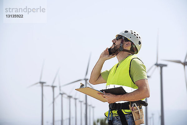 Ingenieur mit Smartphone im Windpark