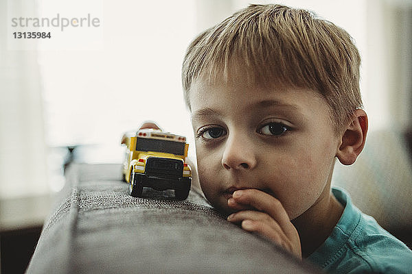 Porträt eines Jungen  der zu Hause mit einem Spielzeuglastwagen spielt