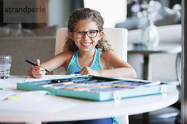 Porträt eines glücklichen Mädchens  das einen Filzstift am Tisch hält