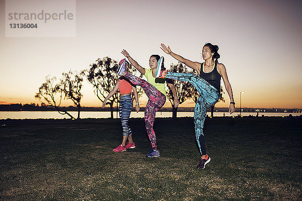 Sportlerinnen trainieren auf dem Feld gegen den klaren Himmel im Park bei Sonnenuntergang