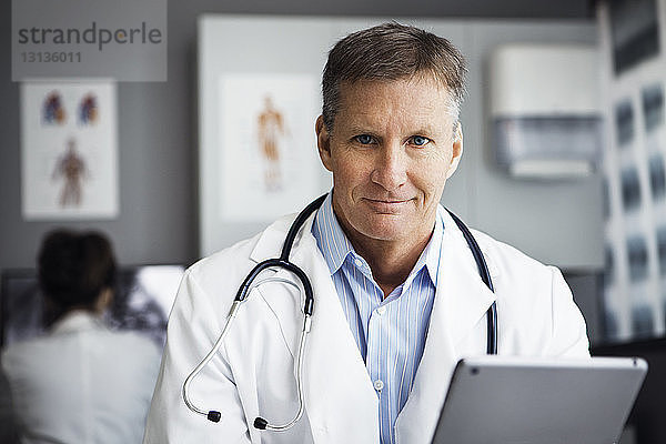 Porträt eines selbstbewussten männlichen Arztes mit Tablet-Computer in der Klinik