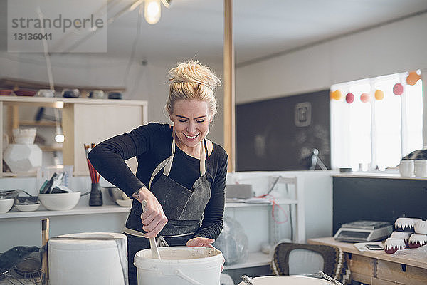 Lächelnde Frau mischt Farbe im Workshop