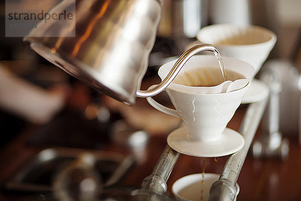 Wasser wird im Café aus dem Kessel in den Kaffeefilter geschüttet