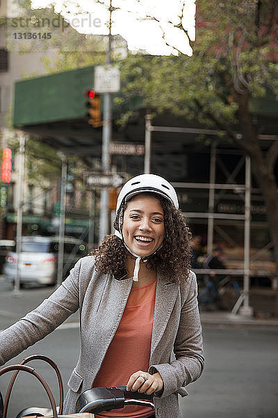 Porträt einer glücklichen Geschäftsfrau  die auf der Straße ein Fahrrad hält