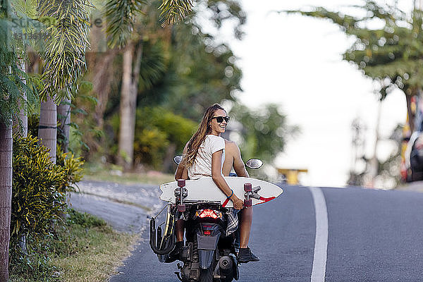 Rückansicht eines Freundes  der Motorrad fährt  während eine Frau ein Skateboard hält
