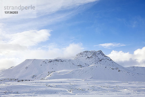Landschaftliche Ansicht von schneebedeckten Bergen vor bewölktem Himmel