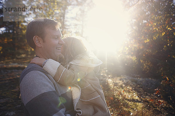 Glücklicher Vater trägt Tochter  während er an einem sonnigen Tag im Park steht